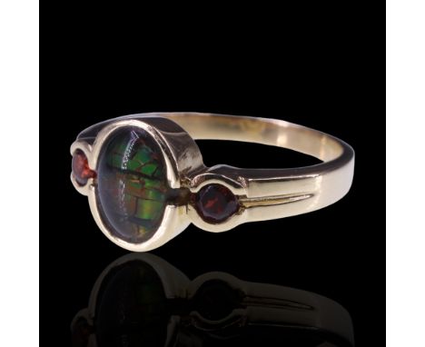 A three-stone ammolite ring, comprising a central oval cabochon bezel-set between two smaller round cabochons on a tapering 1