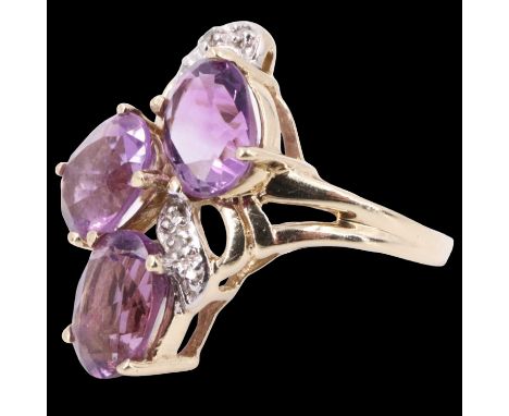 A late 20th Century amethyst dress ring, having three 8 x 6 mm ovals asymmetrically set over an entwining white metal ribbon 