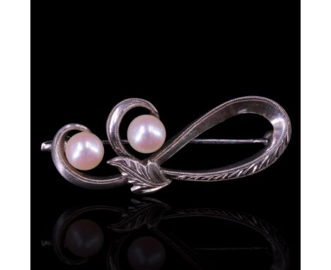 A vintage pearl brooch, in the form of a bright-cut looped open scroll terminating in a pair of pearls and faced with a small