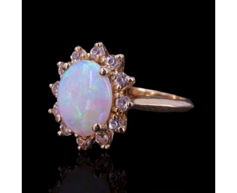 An opal and 14 K yellow metal ring, comprising an oval opal cabochon claw-set above a petal-like arrangement of small white s