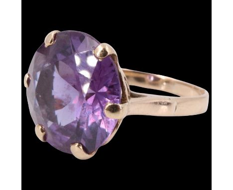 An amethyst finger ring, the 14 mm round stone claw set on a pierced gallery between open tapering shoulders, in a yellow met