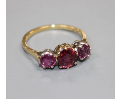 An 18ct and three stone ruby set dress ring, size M, gross 2.7 grams. Condition: Two outer stones are in a white metal settin