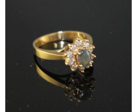 A modern 18k yellow metal, chrysoberyl? and diamond set oval cluster ring, size M, gross weight 4.2 grams. Condition: A few m