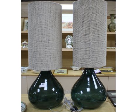 A pair of green glass lamp bases with cylindrical fabric shades, height overall 94cm, diameter 34cm Condition: Glass in good 