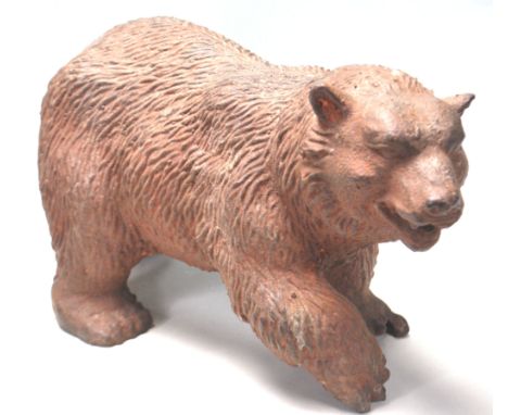 A vintage 20th Century cast iron garden bear figurine in the form of a grizzly bear walking having a brown weathered patina. 