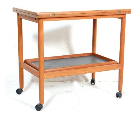 A vintage retro mid Century teak wood hostess trolley of Danish influence having two tiers with a folding top. All raised on 