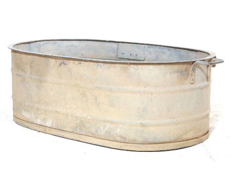 A vintage 20th century industrial reclamation yard galvanised oval twin handle large bath having reinforced rings around and 