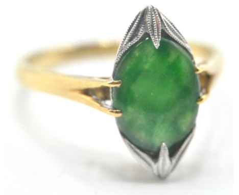 A hallmarked 18ct gold 1960's and jade ring having an oval jade cabochon in a white metal millegrain set mount with split sho