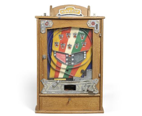 A vintage penny in the slot machine 'Ninecup' made by Bryans, in an oak case and with a key for the drawer and various pennie