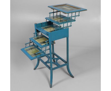 An unusual blue painted wooden occasional table, the hinged top lifts to reveal four tiered shelves inset with ceramic tiles,