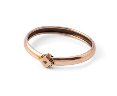 A 9ct gold bangle set with a diamond in starburst setting, internal diameter 57.6 by 49.1mm, total weight 13.3g.