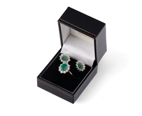 An 18ct gold, diamond and emerald dress ring, the oval cut emerald of approximately 8.2 by 6.4mm, surrounded by ten diamond b