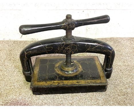 A vintage black and gilt cast iron and brass book press, circa 1900, with screw down press and winding handle