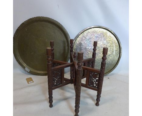 A nomads table with carved hexagonal wooden base and brass top, Diameter 66cm, together with an additional brass top with cha