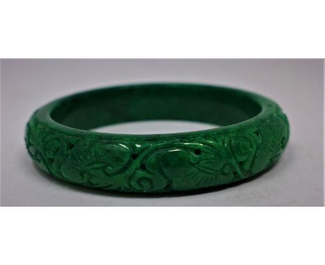 A Chinese, spinach green jade bangle hand-carved with floral tendrils, dia: 6cm, 48g 