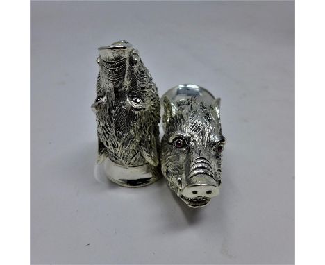A pair of silver plated condiments in the form of textured boars heads each with faceted ruby eyes, H:5.5 x W: 3cm, Gross: 12