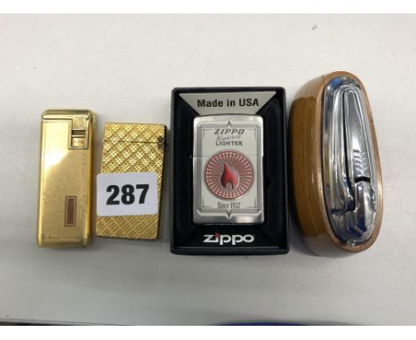 ZIPPO LIGHTER, TWO OTHERS AND A WALNUT TABLE LIGHTER