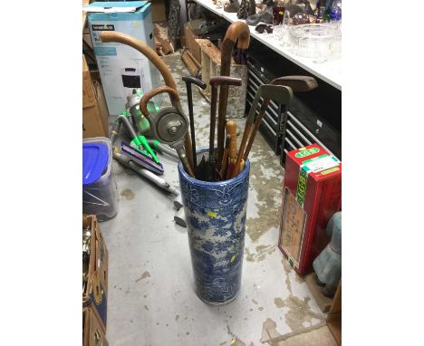 Blue and white porcelain stick stand filled with a range of sticks, umbrellas and clubs