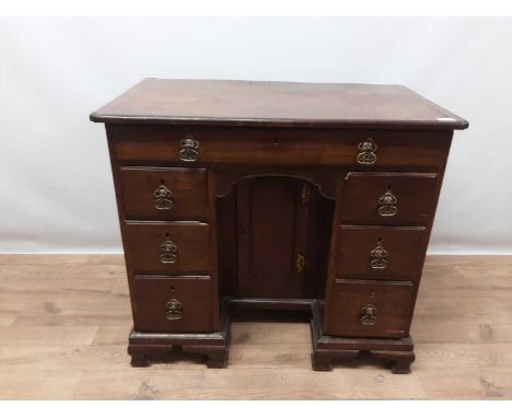 George II mahogany kneehole desk, the crossbanded top with re-entrant corners, central kneehole cupboard and an arrangement o