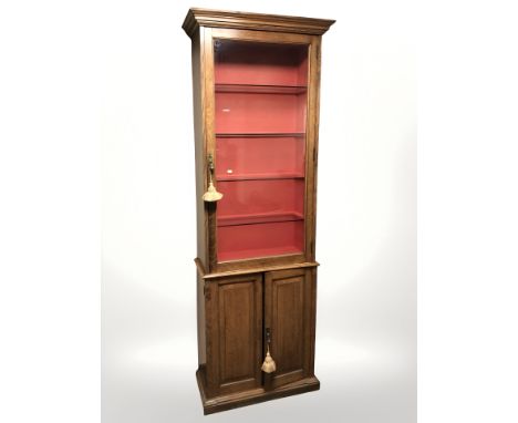 A late Victorian glazed oak single door gun cabinet by Army & Navy CSL Makers, fitted with later glass shelves to interior, w