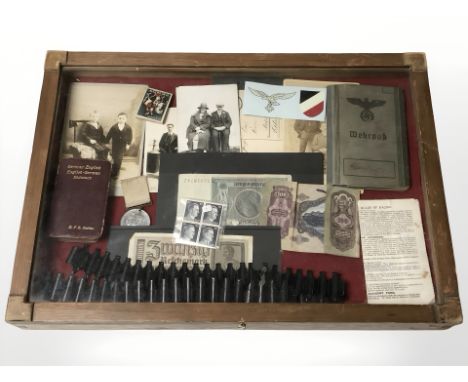 A counter top display cabinet containing German Third Reich items including stamps, photographs, bank notes, soldier's book, 