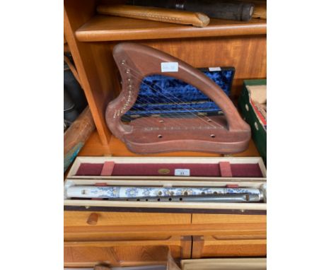 A shelf of wooden carved flutes, boxed musical instruments and an Irish harp 