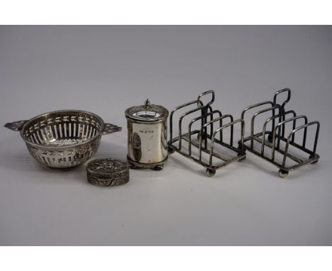 A small group of silver items, to include: a pair of individual toast racks, a tea strainer etc, 189g. (5) 