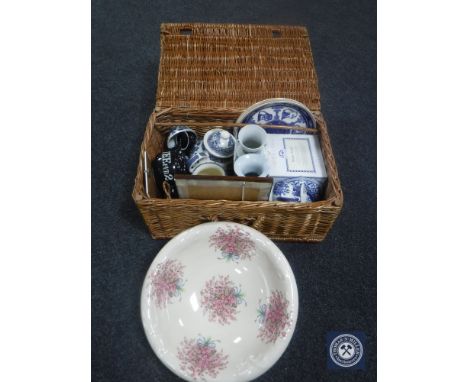A wicker basket containing assorted china including Ringtons teapot and wall plates, Willow pattern teapot, assorted vases, w