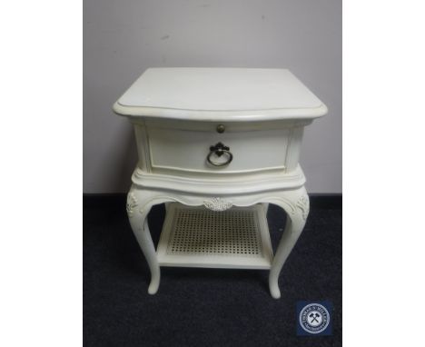 A contemporary cream bedside table fitted a drawer with wicker under shelf