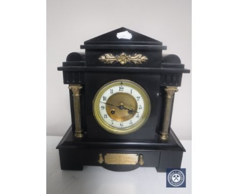 A Victorian black slate presentation mantel clock with brass pillar supports
