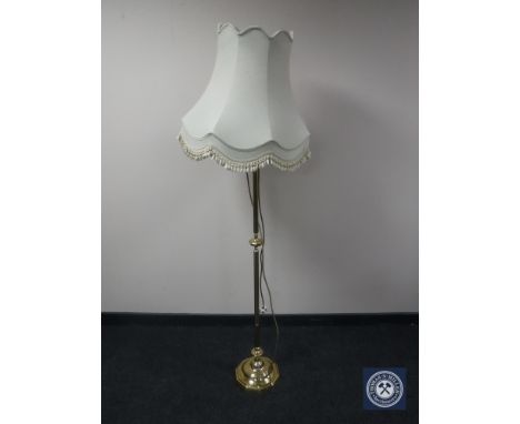 A brass standard lamp with shade