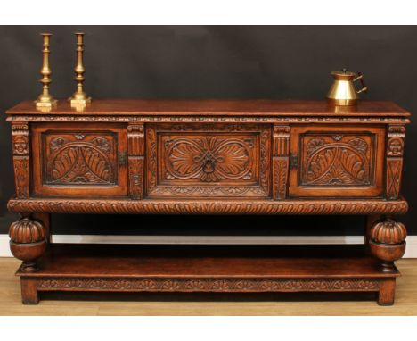 An Elizabethan design oak low pot-board dresser, rectangular top above a central drawer flanked by panel doors, carved with s