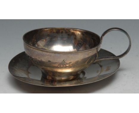 A Middle Eastern silver tea cup and saucer, probably Iraqi, engraved with desert scenes, the saucer 14cm diam, apparently unm