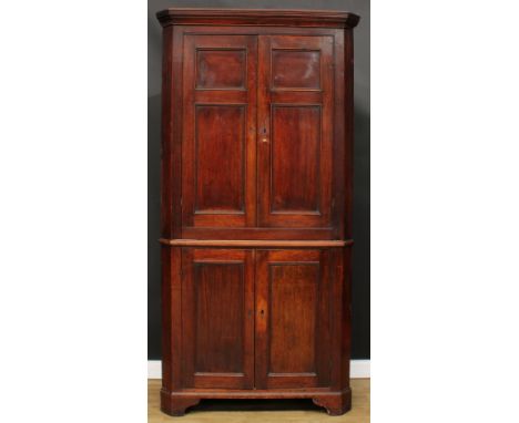 A George III oak country house floor standing splay front corner provision cupboard, moulded cornice above a pair of panel do