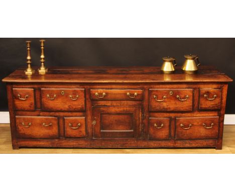A George III vernacular oak low dresser, plank rectangular top above an arrangement of drawers and a panel door, 70cm high, 2