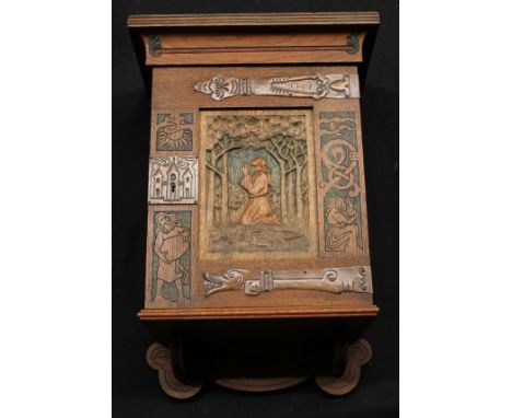 An Arts & Crafts oak wall hanging cabinet, outswept cornice above a rectangular door carved with figures, the central panel c