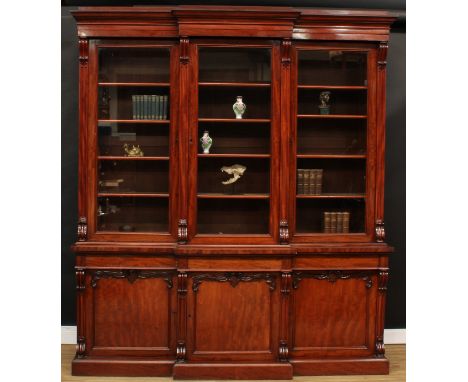 An early Victorian mahogany breakfront library bookcase, moulded cornice above three glazed doors, each enclosing four shelve