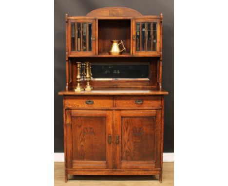 An Arts &amp; Crafts oak sideboard, by Liberty &amp; Co Ltd, London, domed pediment above a pair of glazed vitrine doors, a n