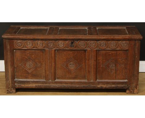 An early 18th century oak blanket chest, hinged three panel top above a frieze carved with geometric roundels, three panel fr