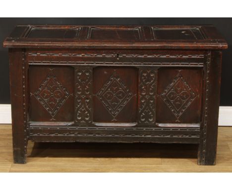 An 18th century oak blanket chest, hinged three panel top, the front carved with leaves and geometric motifs, stile feet, 64.