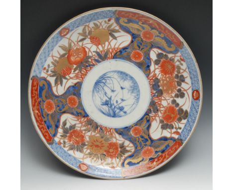 A Japanese Imari charger, painted with flowers, picked out in gilt, central blue and white panel painted with insect amongst 