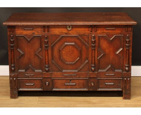 An 18th century oak mule chest, in the Jacobean taste, hinged cover above a three panel front applied with geometric moulding