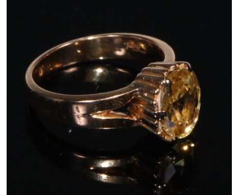 A 18ct gold ring, set with a single oval cut yellow sapphire, size J/K, the stone 10mm high, the plain shank marked 750, 20th