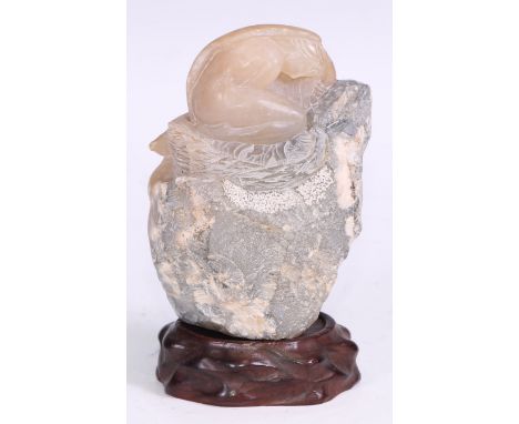 A Chinese agate boulder, carved with a woman, 13cm high, hardwood stand 