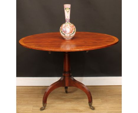 A Regency mahogany tripod centre table, crossbanded oval tilting top, cannon barrel column, stop-fluted downswept legs, brass