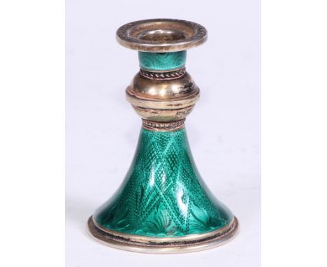 A Continental silver-gilt and guilloche enamel taper stick, trumpet shaped base decorated in emerald tones, 6cm high, marked 