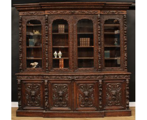 A substantial Victorian oak library bookcase, outswept cornice above four glazed doors enclosing shelves, the projecting base