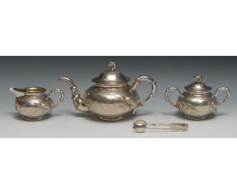 A Chinese silver three piece tea service, comprising teapot, milk jug and sucrier, each chased with a ferocious dragon, on a 