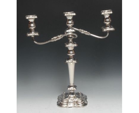 An Elizabeth II silver two-branch three-light table candelabrum, of William IV design, campana sconces, flowering leafy scrol