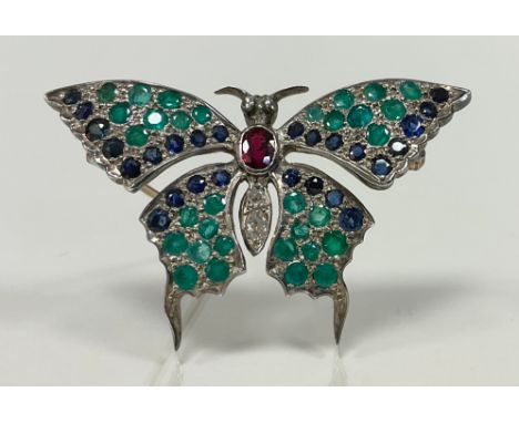 An emerald, sapphire, ruby and diamond butterfly brooch, the solid cast body pave set with central oval deep red ruby, thirty